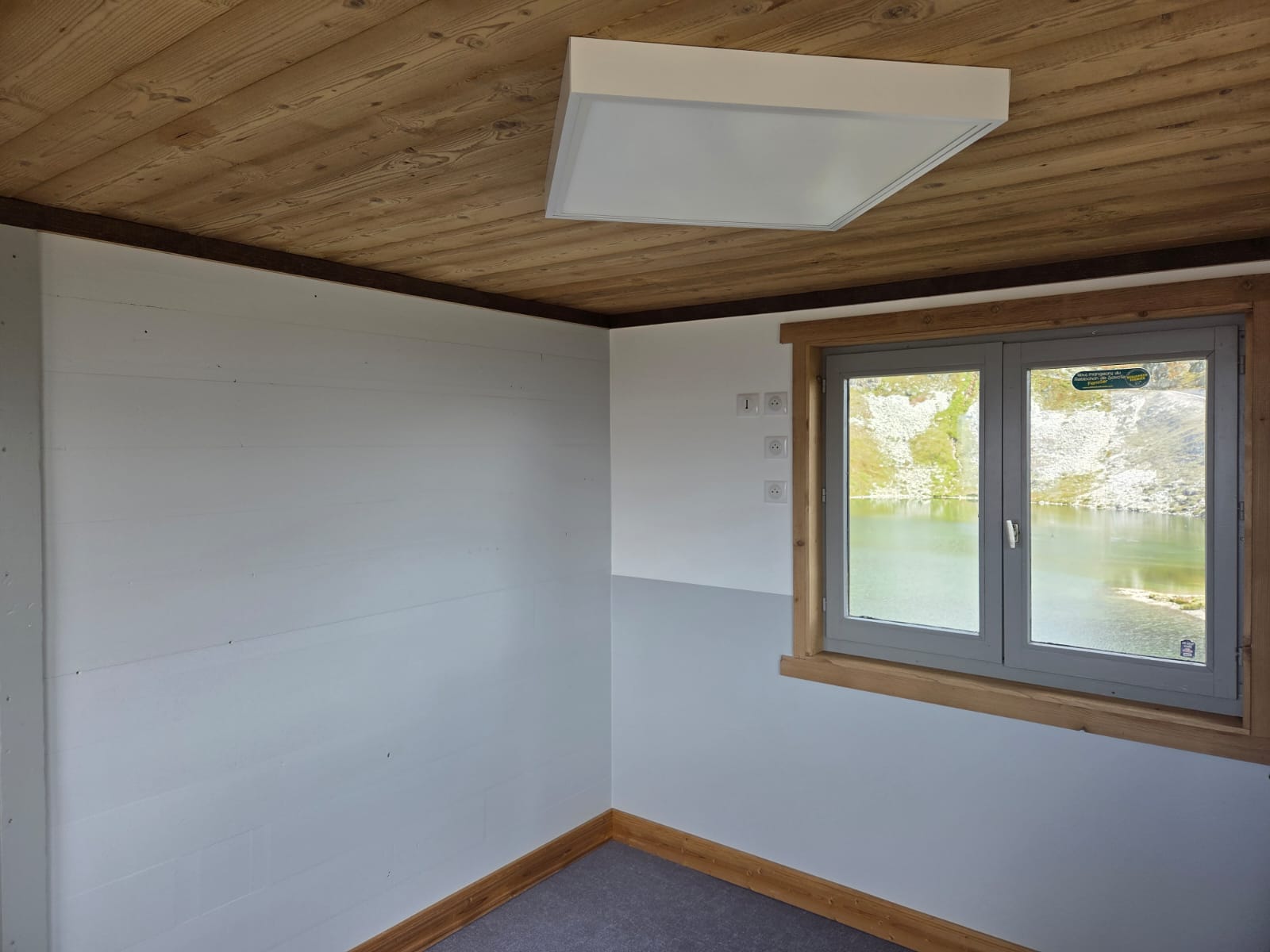 Chambre en cours de peinture avec mur blanc et plafond en bois clair