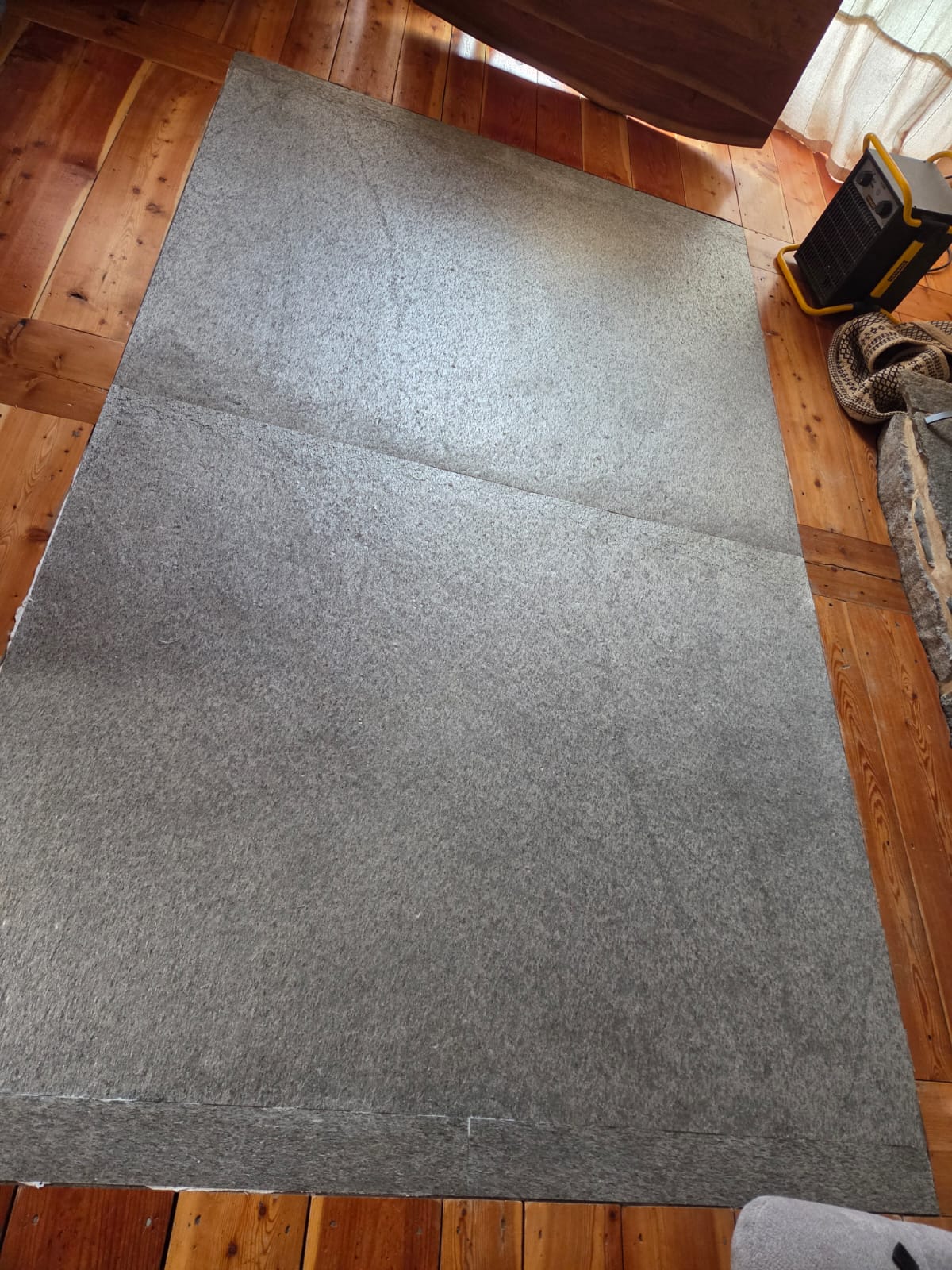 Pose de sol souple PVC gris en cours dans un salon en bois clair