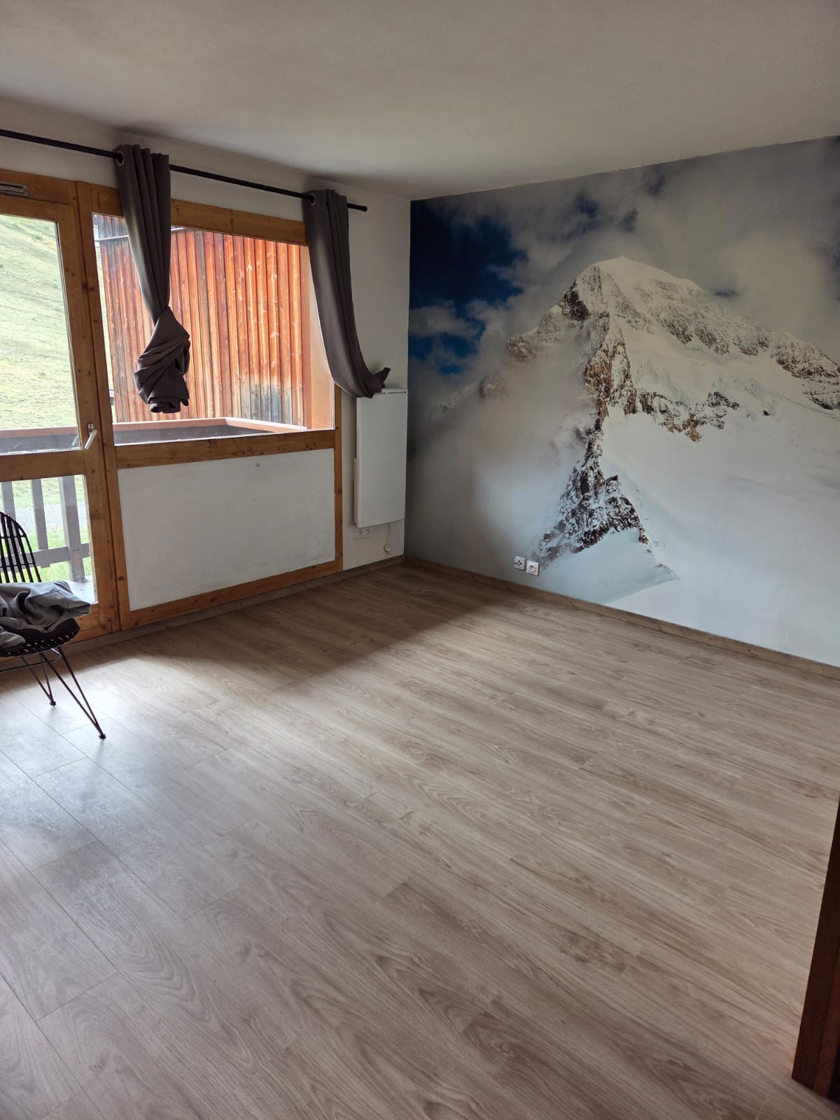 Salle de séjour avec mur décoratif montagne et sol en vinyle imitation bois clair